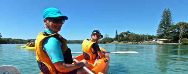 Two paddlers in an orange double kayak on clear water on the Brunswick River